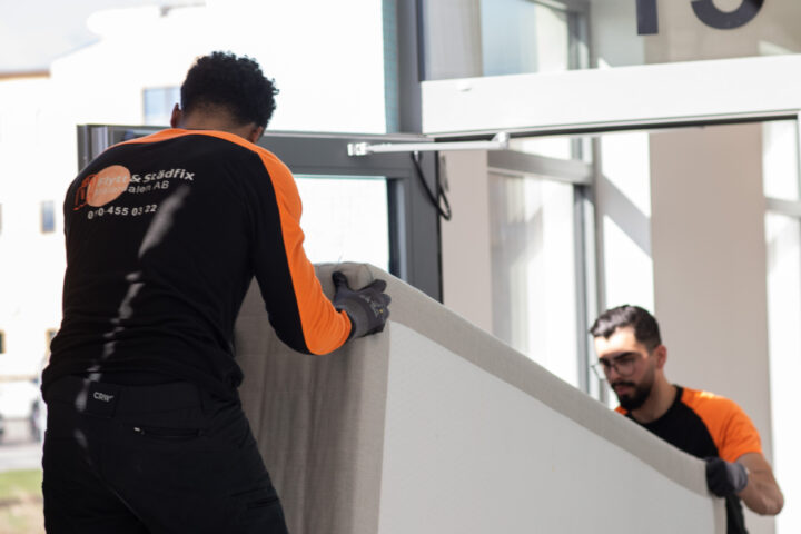 A member of the Flytt och Städfix Mälardalen AB team loading a mattress into a van during a move.