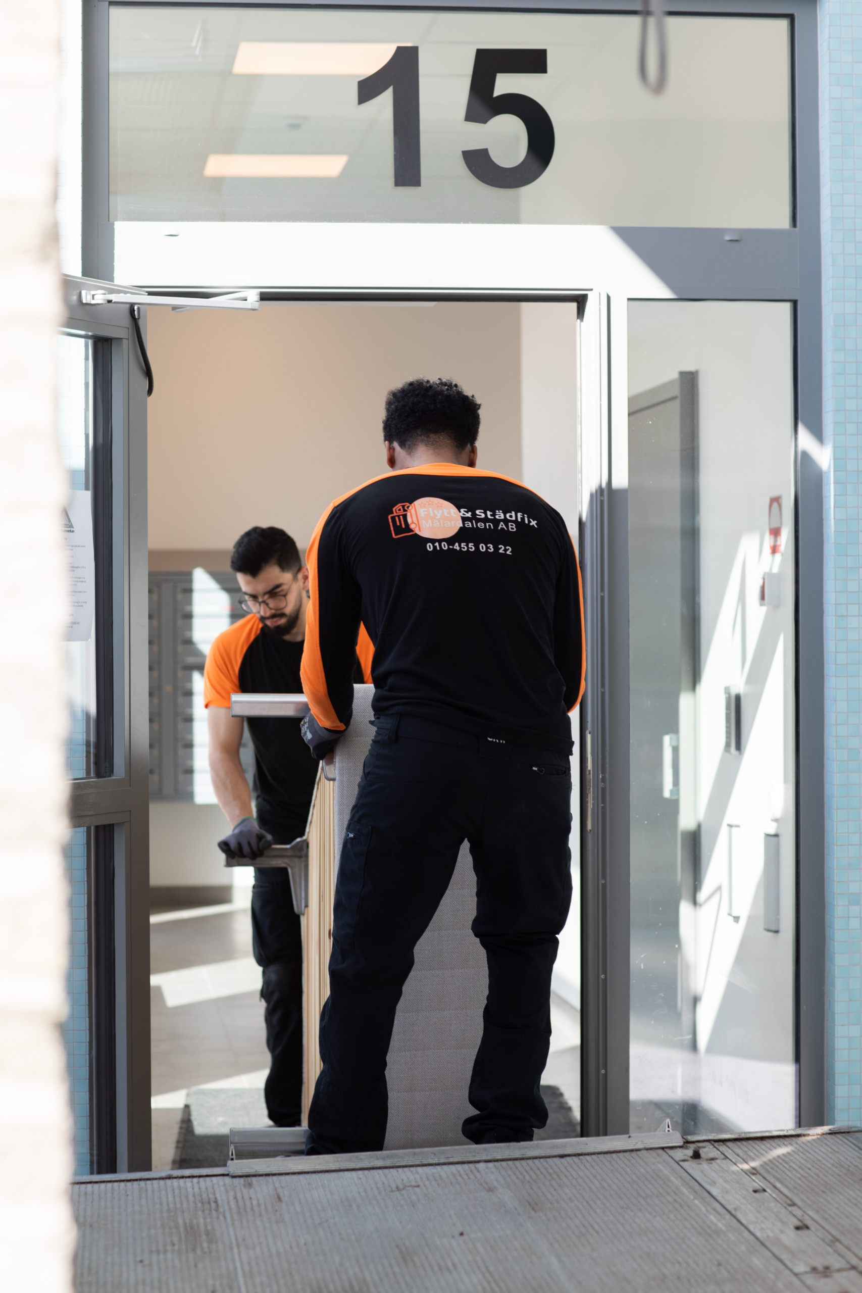 A member of the Flytt och Städfix Mälardalen AB team loading a bed into a van during a move.
